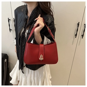 Detailed view of red leather baguette bag featuring a unique gold gourd-shaped buckle