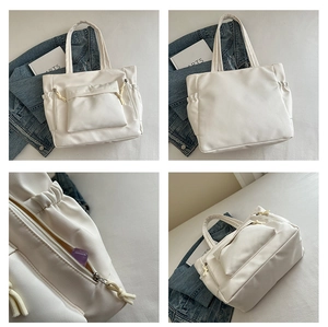 Detail view of large white leather tote bag featuring functional zippers and side drawstring