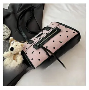 Detail of pink polka dot tote bag with black leather straps and plush bear charm