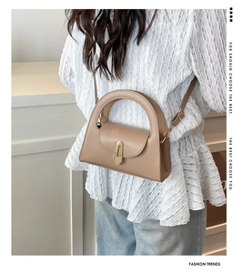 Detail view of cream-colored faux leather bag featuring elegant gold metal clasp and top handle