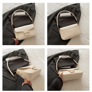 Detail view of cream flap shoulder bag with gold hardware and chain strap accents