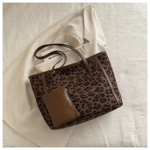 Detailed shot of leopard print tote bag with brown leather handles and matching pouch