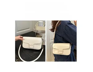 Detail of off-white leather square bag showing adjustable strap and metal chain links
