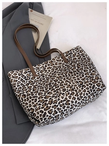 Close-up of leopard print tote bag with brown leather handles and premium stitching