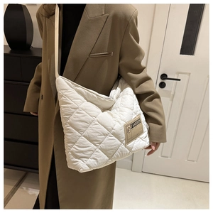Gros plan du sac bandoulière blanc matelassé avec étiquette de mode sur manteau marron