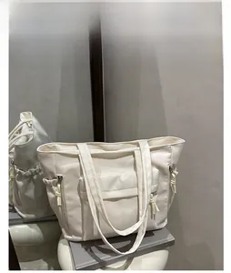 Detail of white nylon tote bag with front flap pocket and drawstring on minimalist props