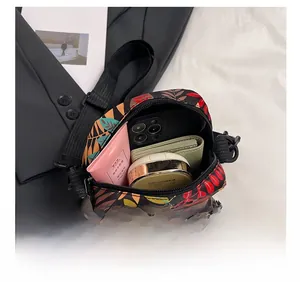Top view of compact crossbody bag with tropical prints showing phone and cosmetics inside