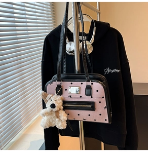 Détail du sac à main rose à pois avec garniture en cuir noir et breloque ours blanc
