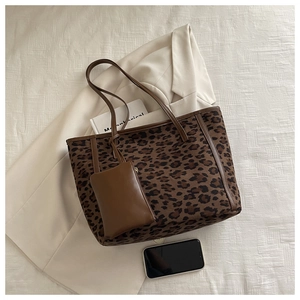 Large leopard print tote bag with matching inner pouch on a stylish textured background