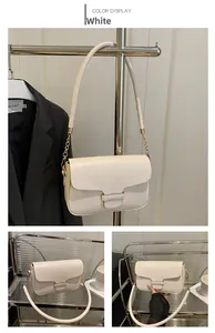 Detail view of white minimalist square crossbody bag with gold chain and leather buckle