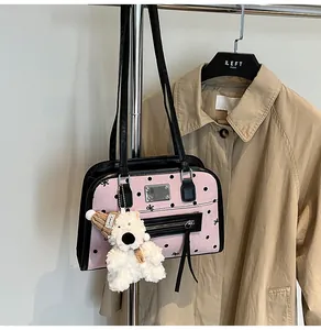 Detail of pink polka dot handbag featuring embroidered bows and a cute teddy bear charm