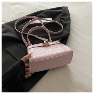 Détail du sac en cuir gaufré crocodile rose avec fermoir rotatif doré et texture chic