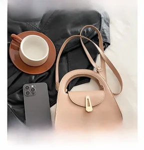 Detail view of beige semicircular tote bag with golden metal clasp and leather texture