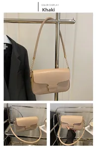 Close-up of khaki leather square bag featuring golden chain strap and metal clasp detail