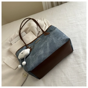 Détail du sac cabas en denim avec finitions en cuir et porte-clés nuage en peluche
