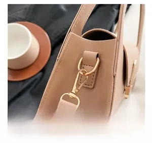 Close-up of premium light gold metal hook hardware on a minimalist cream handbag