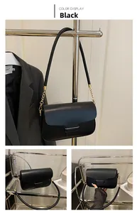 Detail of a black glossy leather crossbody bag with gold chain strap and buckle