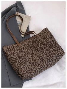 Close-up of leopard print tote bag flat laid on white texture with autumn fashion props