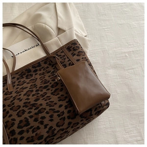 Detail view of leopard print tote bag with brown leather handles and matching pouch