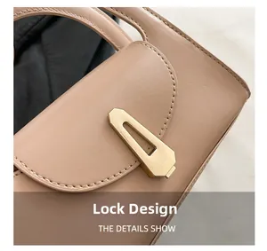 Macro detail of gold geometric metal lock and fine stitching on beige leather handbag
