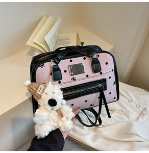 Detail of pink polka dot handbag with bow patterns and cute plush bear charm accessory