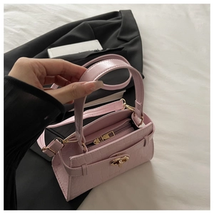 Détail du sac à main rose clair à motif crocodile avec fermoir doré sur blazer noir
