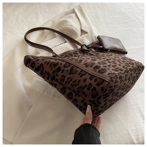 Close-up of leopard print tote bag with brown leather handles and matching mini coin purse