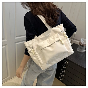 Detailed shot of white large capacity tote bag with front flap pocket and drawstring side details