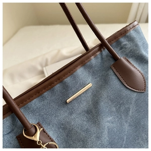 Gros plan détaillé du sac cabas en denim avec anses en cuir marron et garnitures dorées