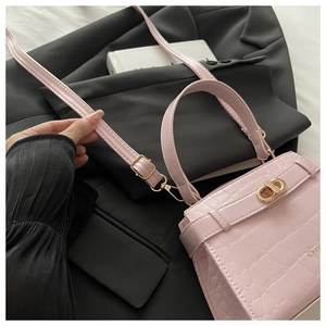 Détail d'un sac à main rose motif crocodile avec fermoir doré et bandoulière réglable