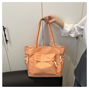 Detail of peach pink nylon tote bag with functional pockets and cord zipper pulls