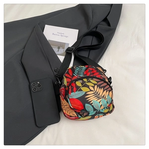 Detail of colorful leaf print on black canvas crossbody bag with adjustable strap