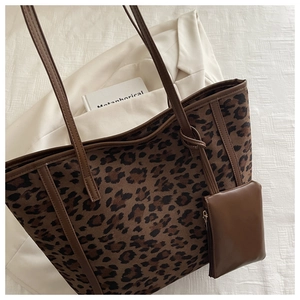 Detail of leopard print tote bag with brown shoulder straps and a matching small pouch