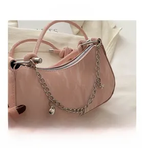 Close-up of pink crescent handbag featuring silver heart and star charm chain details