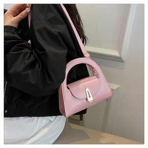 Detail view of pink trapezoid handbag featuring gold metal buckle and leather handle