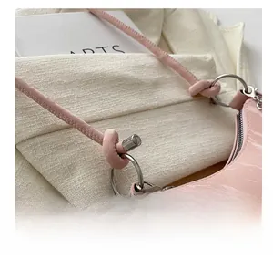 Detailed close-up of pink crocodile embossed leather bag with silver metal chain ring