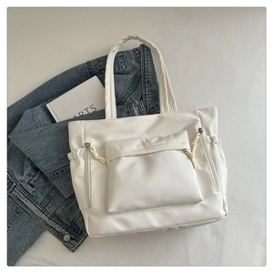Detail of white PU leather tote bag with functional front pocket and knotted zipper pulls