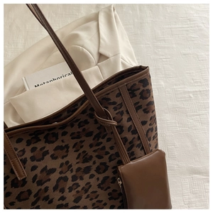 Detail shot of leopard print tote bag with brown leather trim and matching coin purse charm