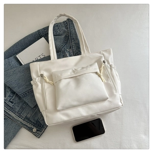 Detail of off-white tote bag showing leather texture and side drawstring pocket