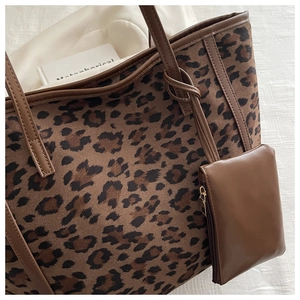 Detail view of leopard print tote bag with brown leather trim and mini pouch accessory