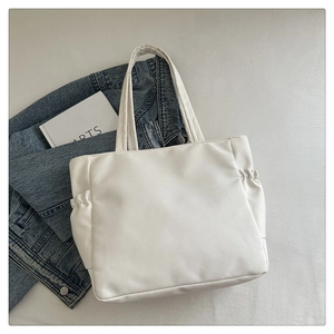 Detail view of white leather tote bag with unique side pleats and wide shoulder straps