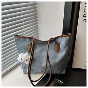 Gros plan du sac cabas en toile bleue avec anses en cuir marron et breloque nuage