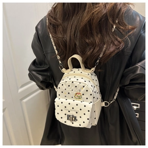 Mini sac à dos blanc à pois avec bandoulière chaîne porté sur une veste en cuir