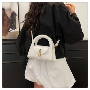 Detailed side view of white minimalist handbag with gold shield clasp and leather handle