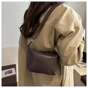 Detail view of a brown woven leather hobo bag worn with a chic beige trench coat
