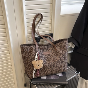 Leopard print canvas tote bag with brown leather straps and plush bear keychain