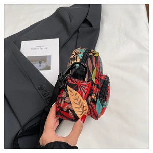 Detail of leaf pattern mini crossbody bag with adjustable strap on white bedding