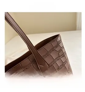 Close-up of the dark brown crocodile embossed leather texture and sturdy carry handle