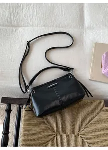 Detailansicht der schwarzen Ledertasche mit Silberringen und verstellbarem Schultergurt