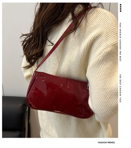 Detail of dark red patent leather baguette bag with shiny finish and shoulder strap